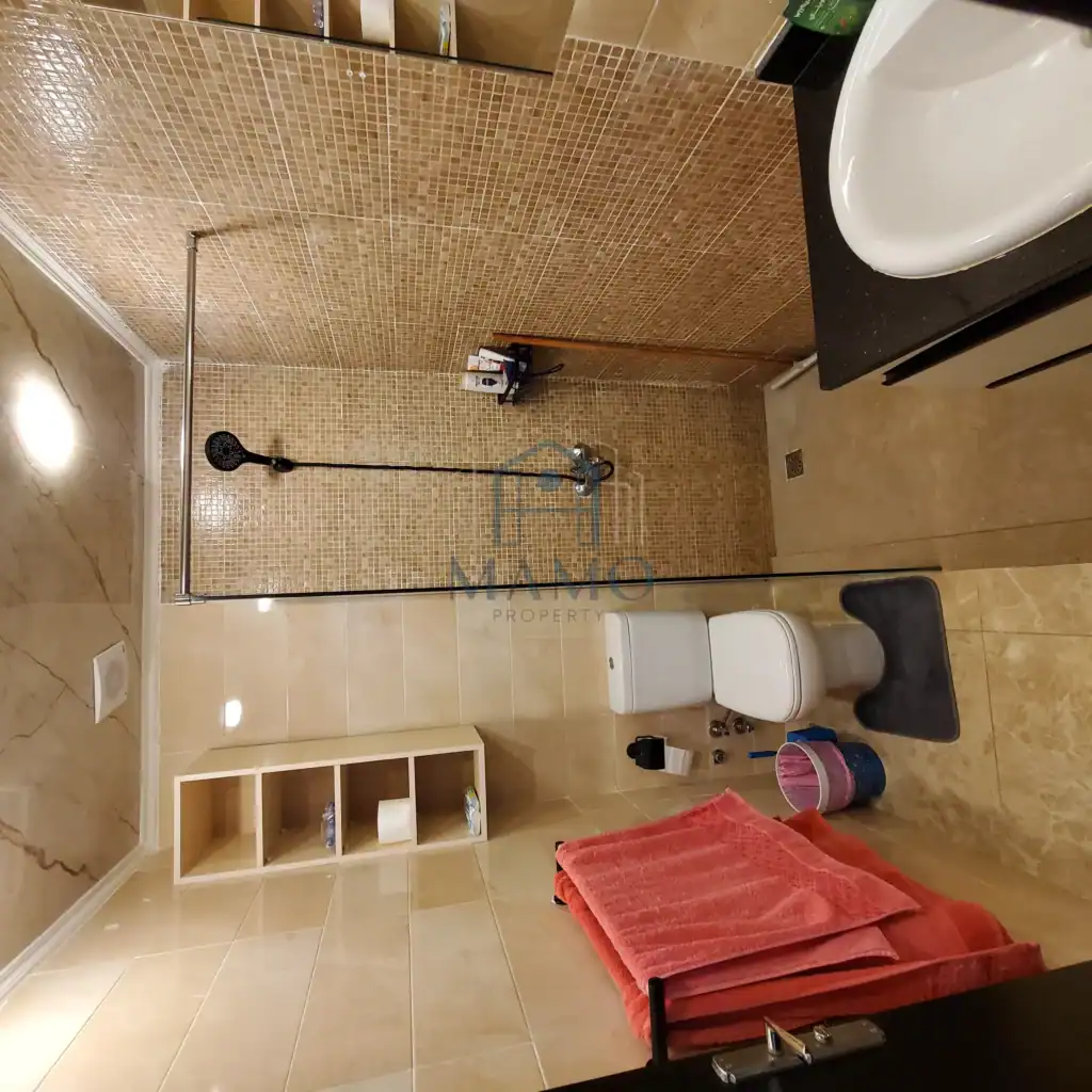 Modern bathroom with walk-in shower and beige tiles.