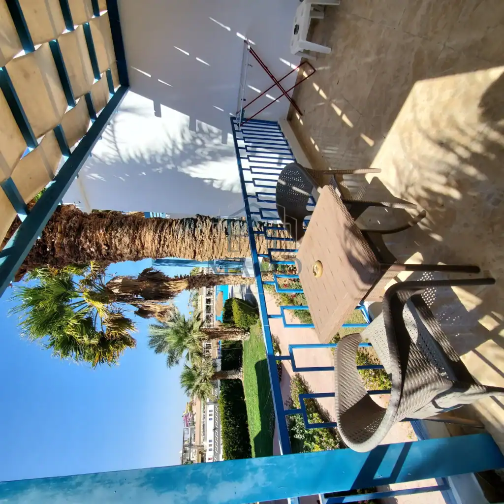 Outdoor balcony with chairs and table overlooking palm trees and the sea in Hurghada.