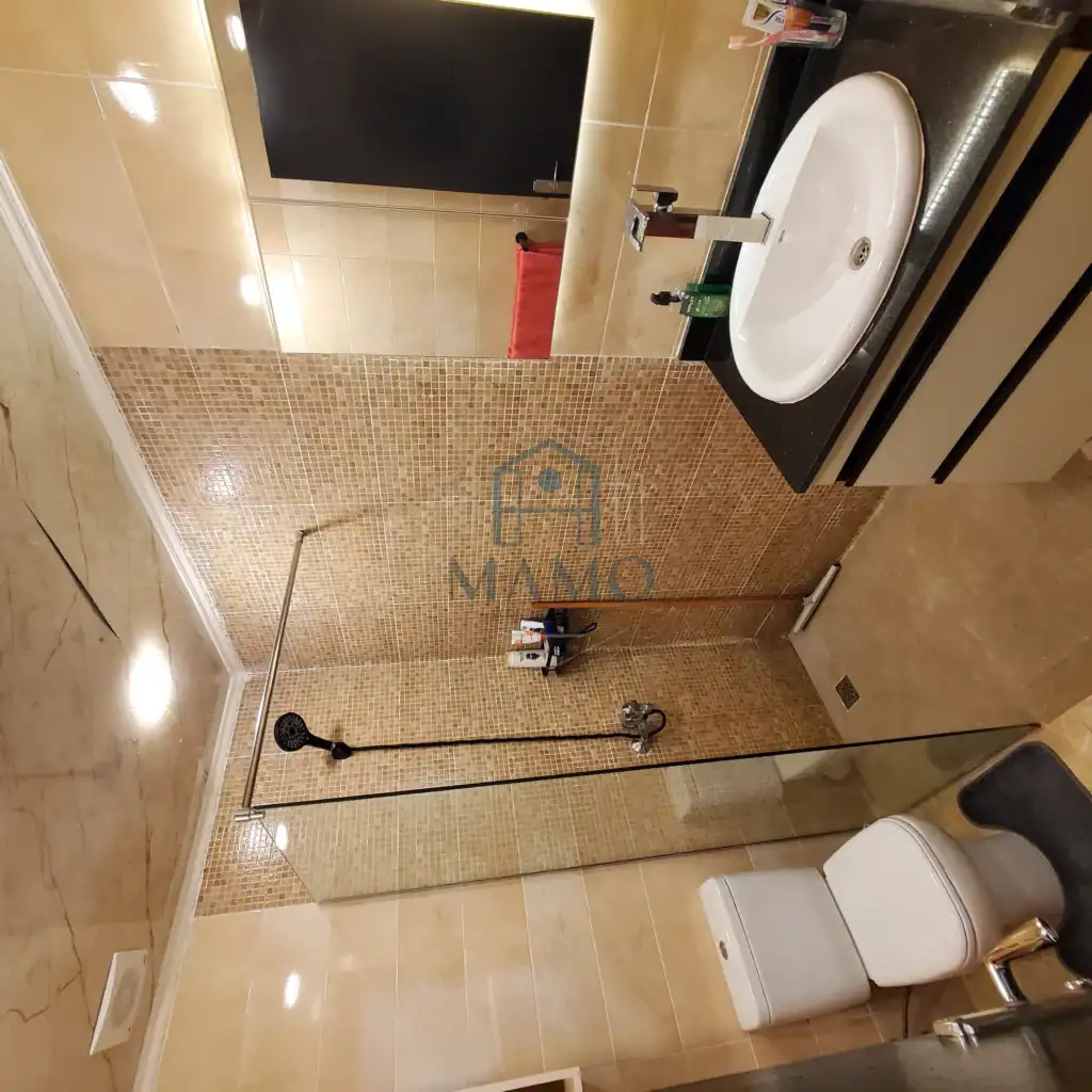 Bathroom with shower, toilet, and sink in a contemporary hotel apartment.